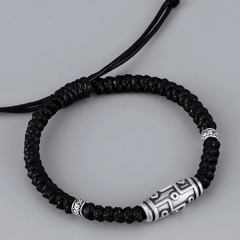 Adjustable dzi bead bracelet flat lay front view, displaying nine-eye silver bead with decorative rings and black braided rope