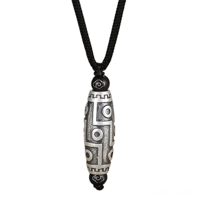 Nine-eye dzi bead pendant full front display on neutral backdrop highlighting traditional Tibetan motifs and copper work