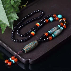 Nine-Eye Dzi Bead Dragon Protection Necklace with Om Mani Padme Hum Pendant displayed on dark tray with green foliage