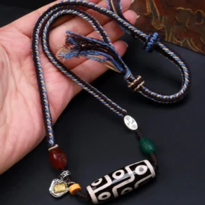 Nine-eye dzi bead tibetan necklace held in hand showing braided rope cord and metal accents