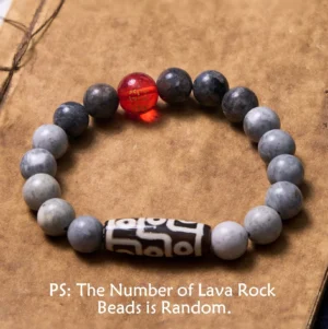 Nine-Eye Dzi Bead Picasso Jasper bracelet flat lay on vintage notebook, showcasing matte grey jasper beads with red accent bead and authentic Tibetan dzi amulet