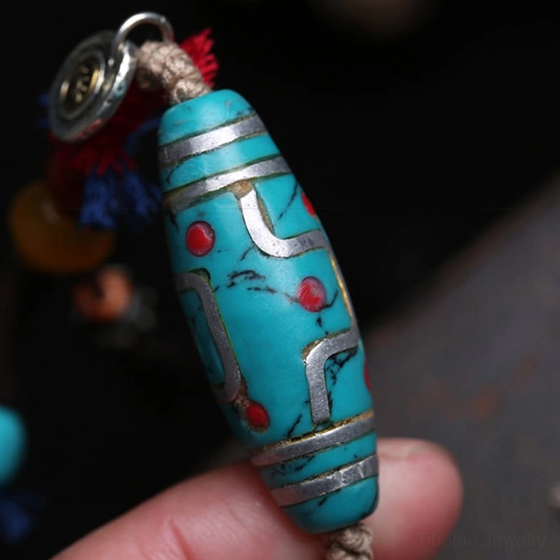 Handheld turquoise dzi bead pendant with nine-eye pattern and silver charm, wearable Tibetan spiritual jewelry