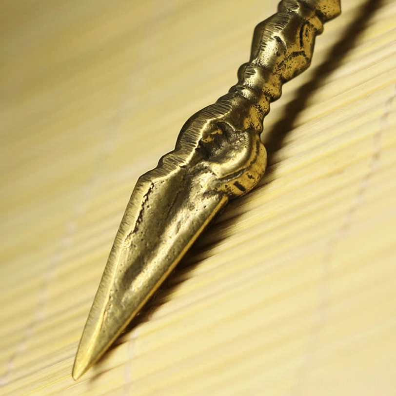Close-up overhead view of nine-prong vajra dorje featuring bright bronze color and intricate carved patterns on handle and spear crown
