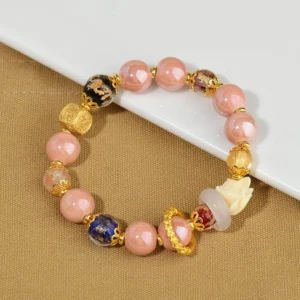 Nine-tailed fox incense ash liuli glass beaded bracelet with pink beads, gold accents, and white fox charm displayed on white tray