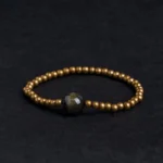 Gold sheen obsidian copper brass beaded bracelet flat lay top view with dark focal stone