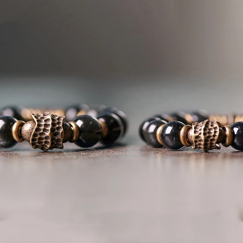 Two matching rainbow obsidian bracelets side by side with bronze metal charms and glossy beads