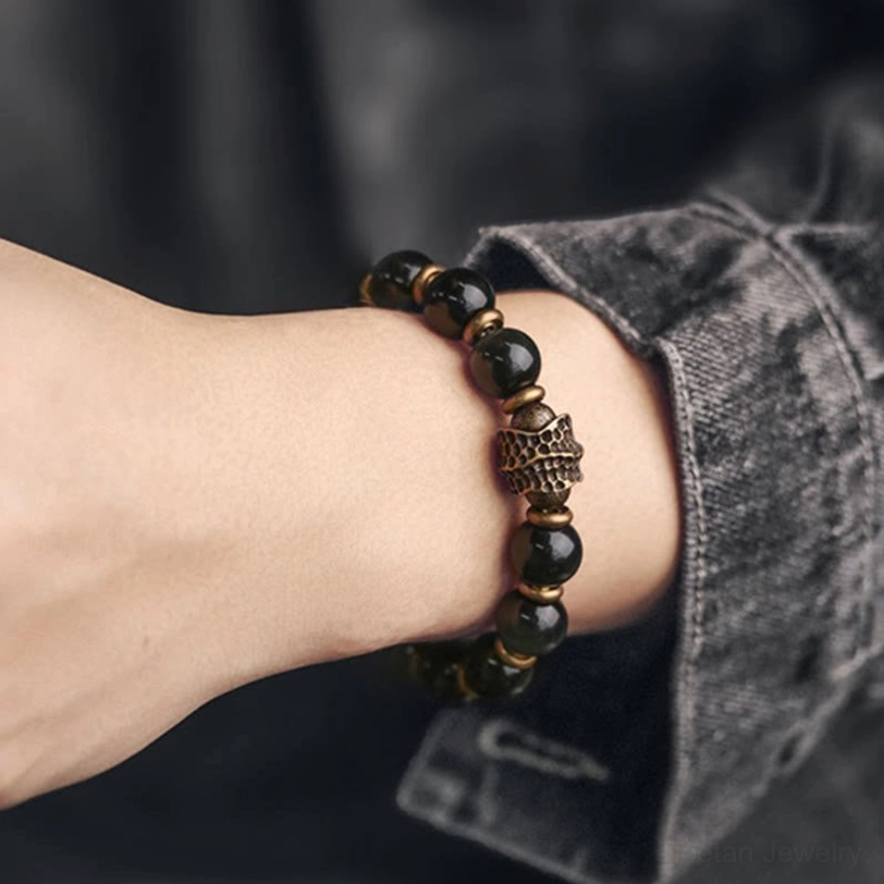 Layered rainbow obsidian bracelets stacked on wrist with bronze metal details and glossy beads