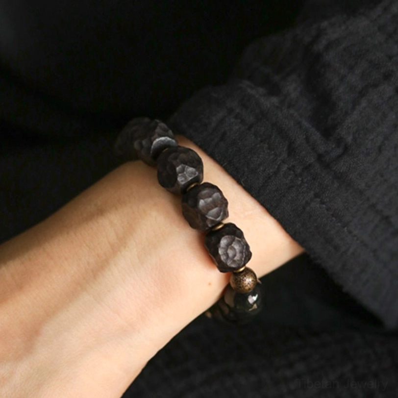 Simplified black obsidian and copper spacer bead bracelet variation worn on wrist close-up