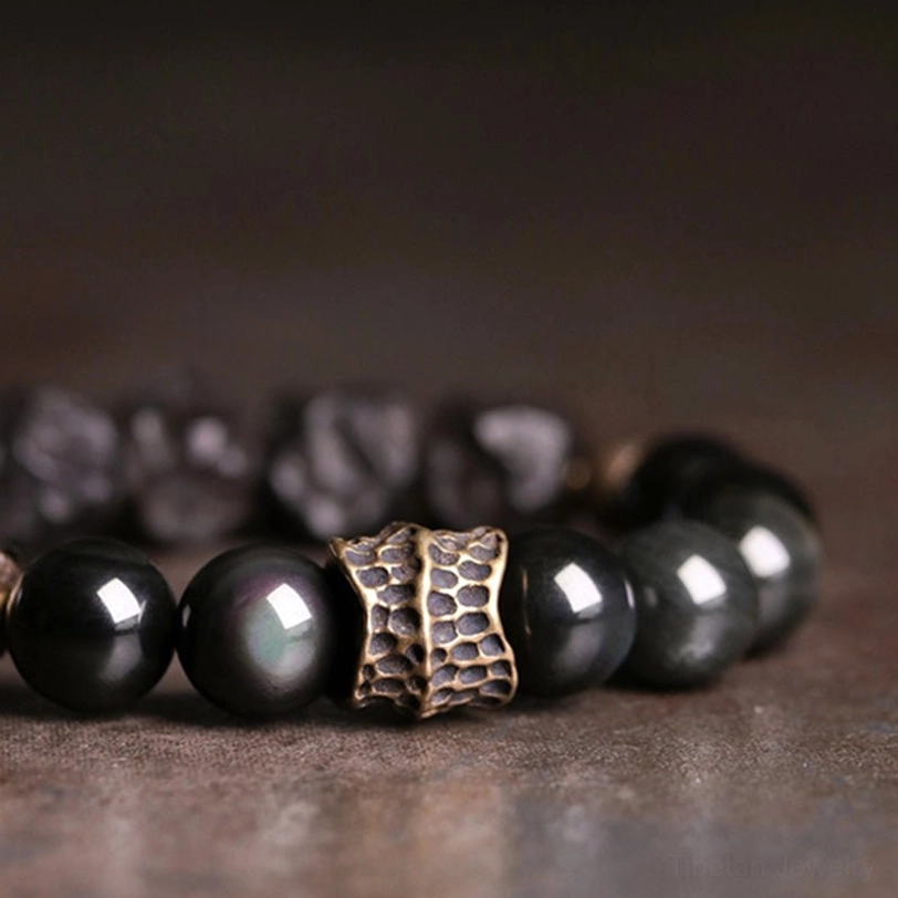 Partial black obsidian ebony wood bracelet with embossed metal bead and mixed smooth and rough stones