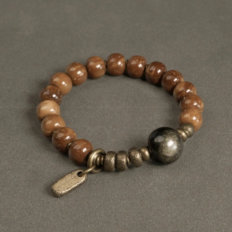 Gold sheen obsidian and kuka seed beaded bracelet with polished dark central stone and antique brass