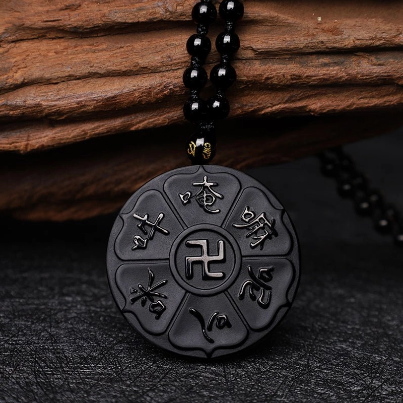 Matte black obsidian disc pendant necklace featuring Tibetan Om Mani Padme Hum mantra and swastika, front-facing top-down composition