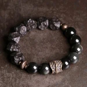 Close-up detail of irregular carved black obsidian and ebony wood beads with polished copper hardware spacers