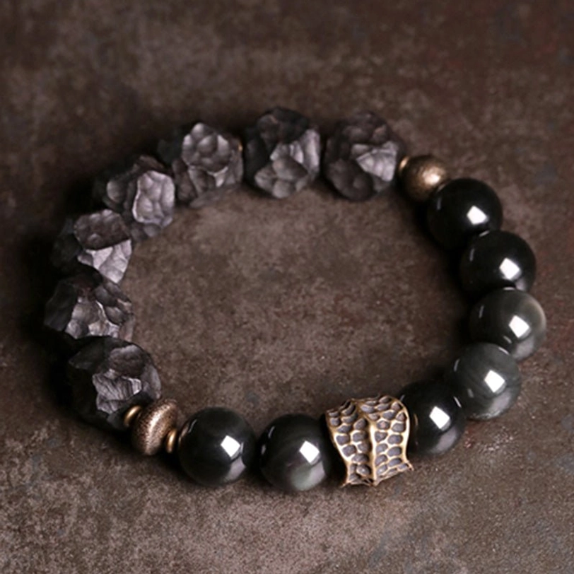 Close-up detail of irregular carved black obsidian and ebony wood beads with polished copper hardware spacers