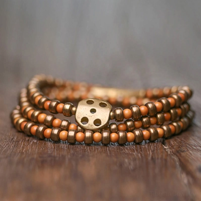 Stacked handmade olive pit brass bracelets three-quarter view showing traditional four-hole brass fastener and warm earthy tones