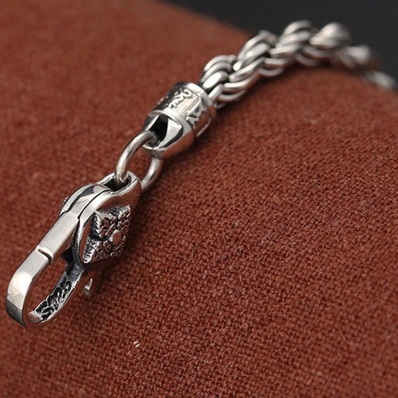 Extreme close-up of carved lobster clasp and engraved connector piece on 925 sterling silver Dorje Vajra bracelet