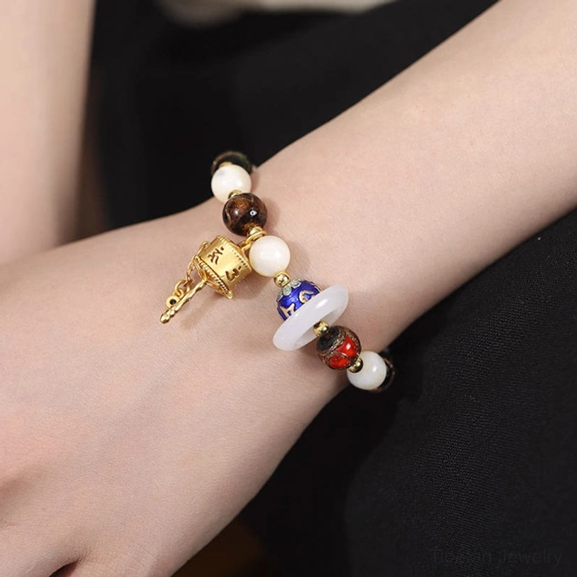 Wrist-worn view of spiritual bracelet with engraved prayer wheel charm and colorful enamel mantra beads