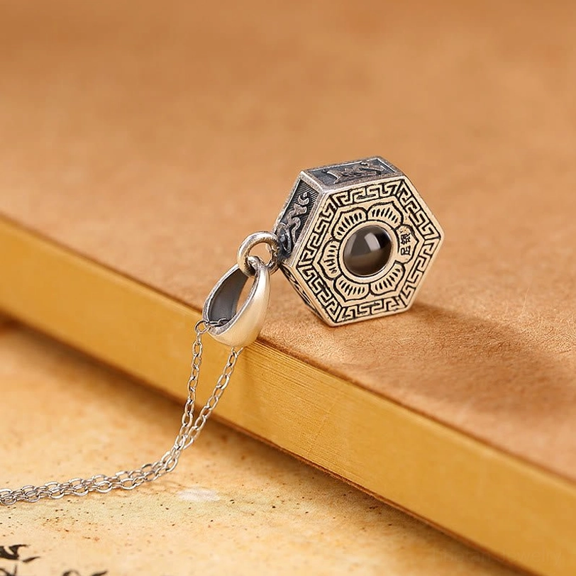 Om Mani Padme Hum silver necklace side view showing attached chain with floral border design around central lens on vintage backdrop