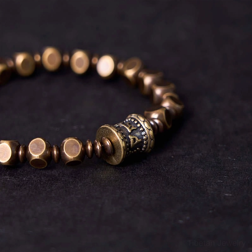 Close-up detail of Om Mani Padme Hum brass bead showing hand-carved inscription and artisan craftsmanship