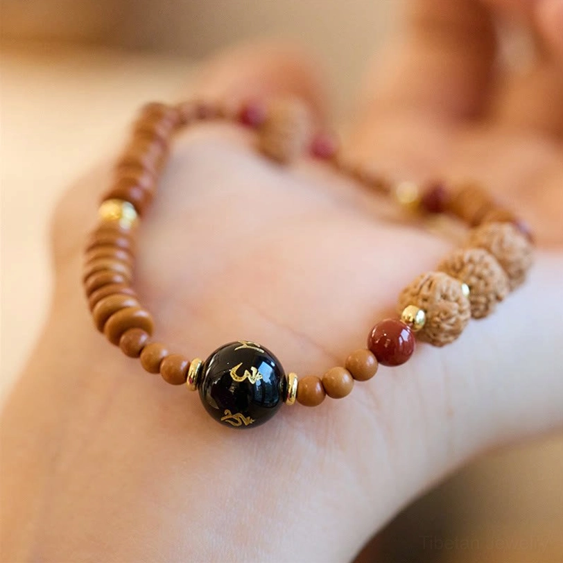 Tibetan bodhi seed bracelet detail view showing Om Mani Padme Hum carved on black onyx centerpiece