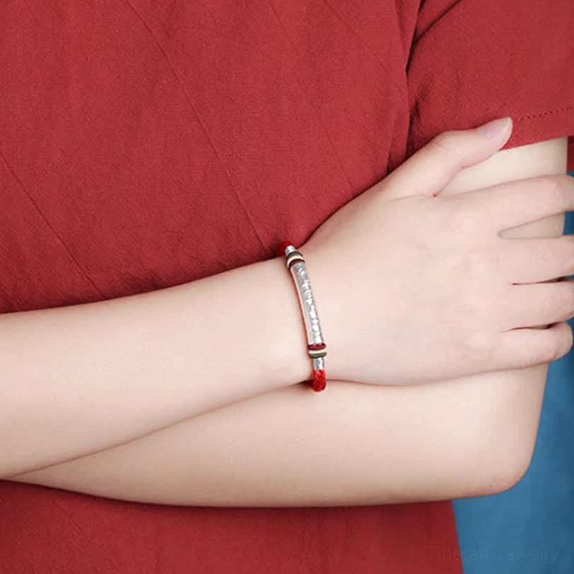 Tibetan Buddhist protection bracelet on right arm with colorful decorative rope and silver engraved tube