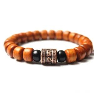 Tibetan Om Mani Padme Hum bone bead bracelet with carved metal charm and black spacer beads on white background