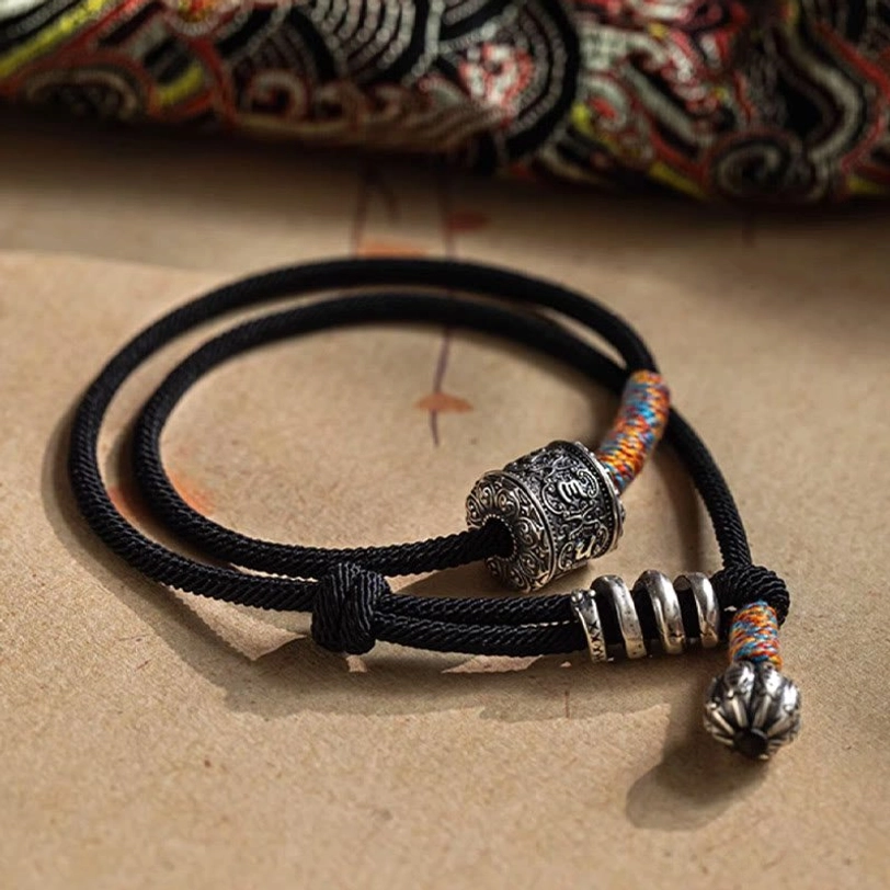 Double wrap Tibetan bracelet with metal spacer rings and colorful woven thread accents on retro background