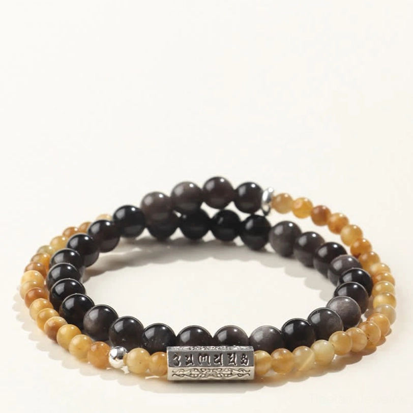 Overhead flat lay view of Om Mani Padme Hum double wrap bracelet featuring polished silver mantra charm and light tan stone with dark obsidian beads