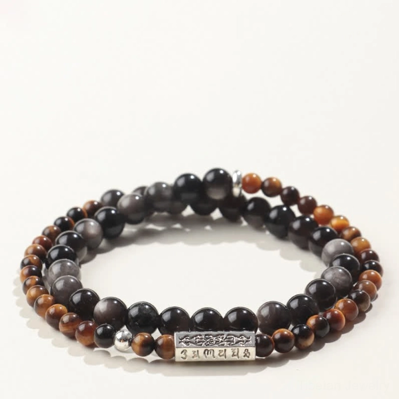 Flat lay photo of Tibetan Om Mani Padme Hum bracelet with reddish-brown striped beads and dark obsidian double wrap design