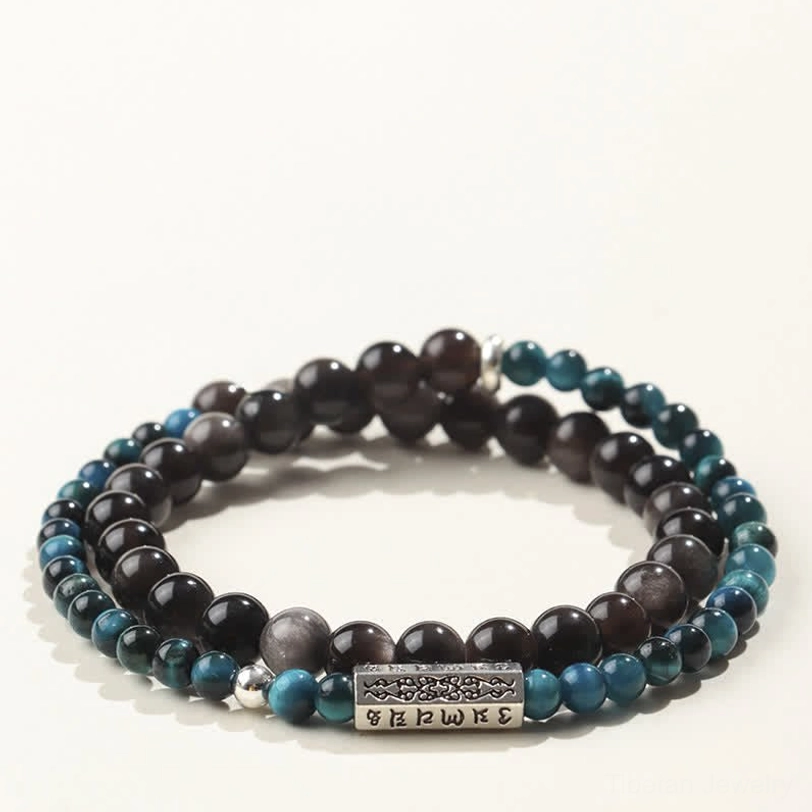 Flat lay of Sacred Om Mani Padme Hum double wrap bracelet with deep black obsidian and teal blue stone beads