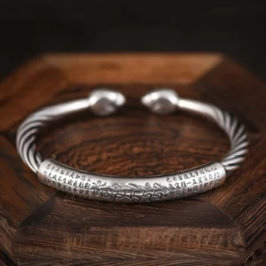 Overhead view of open-ended Tibetan mantra copper cuff bracelet on wooden surface