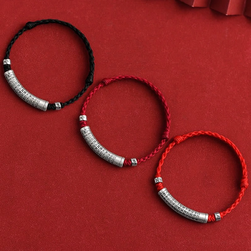 Set of three adjustable tibetan mantra bracelets in black and red rope with engraved silver tubes showing mantra variations