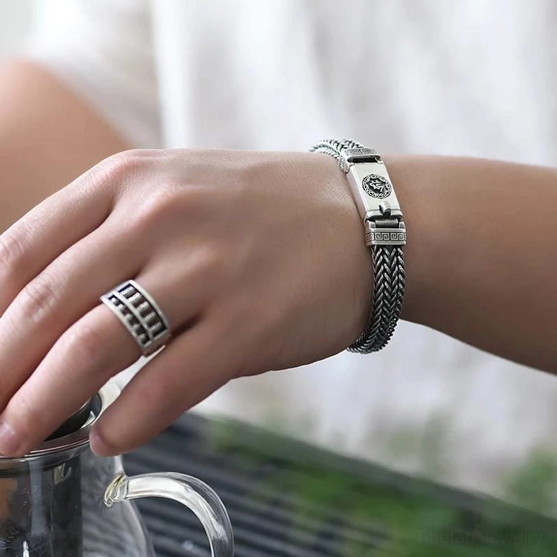 First-person wearing demonstration of Om Mani Padme Hum bracelet on left wrist, styled with matching patterned ring in everyday setting
