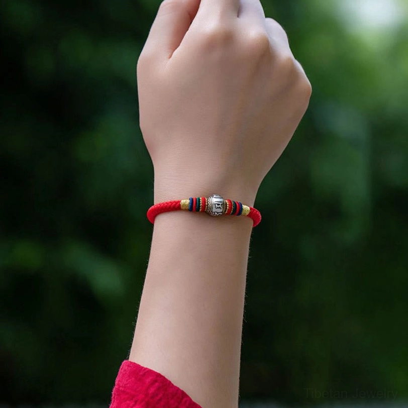 Worn on wrist Om Mani Padme Hum Tibetan protection bracelet outdoors with green foliage background