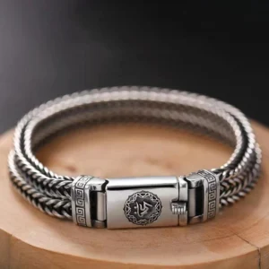 Om Mani Padme Hum Tibetan braided bracelet with engraved mantra buckle, displayed on wooden surface showing intricate woven wheat chain and vintage silver tone finish