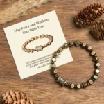 Om Mani Padme Hum brass amulet bracelet with gift message card on natural wood background with pine cones