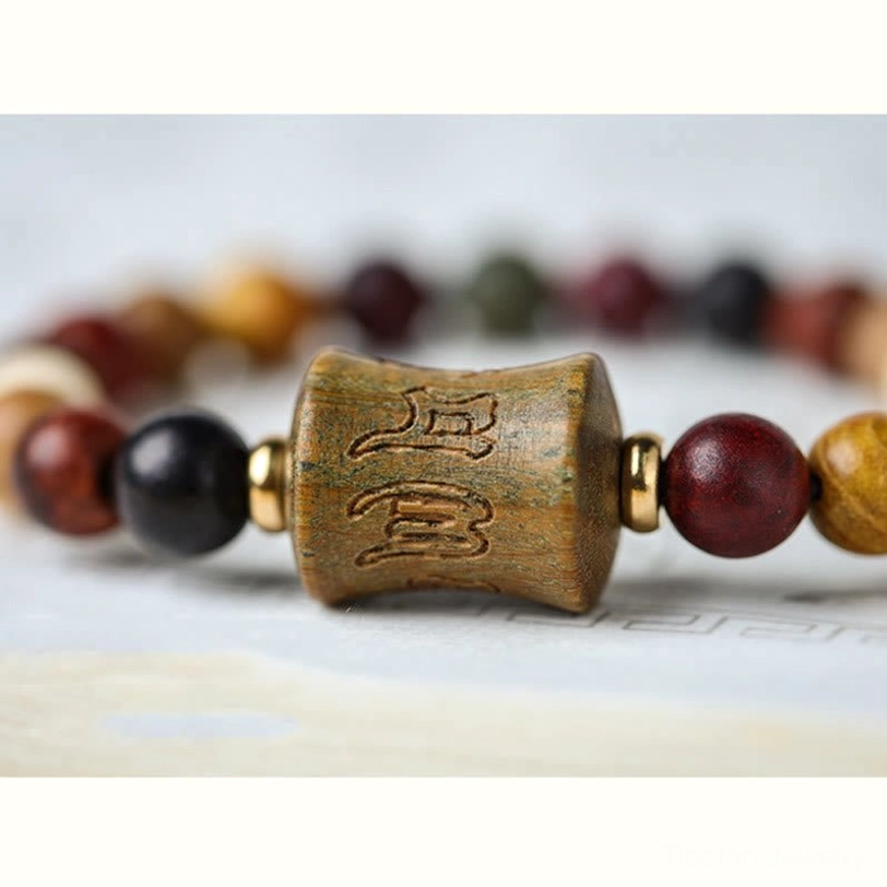 Macro close-up of Om Mani Padme Hum carved wooden bead with copper metal spacers showing intricate mantra carving detail and craftsmanship