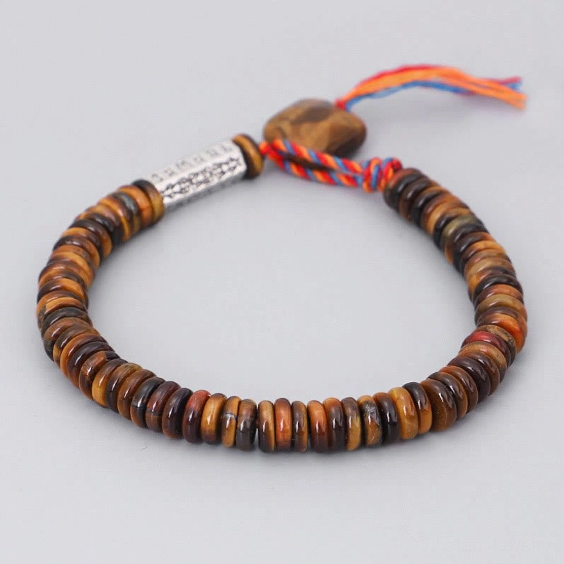 Close up detail of tibetan bracelet charm showing engraved om mani padme hum silver tag on weathered wood