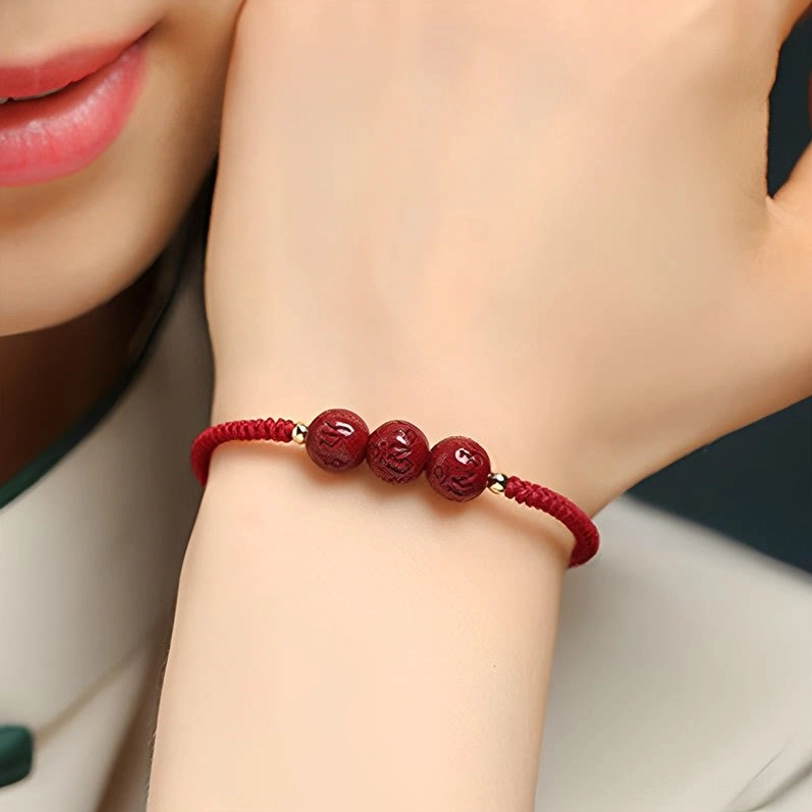 Om Mani Padme Hum cinnabar bead bracelet featuring three carved red beads with gold spacer accents worn on female wrist