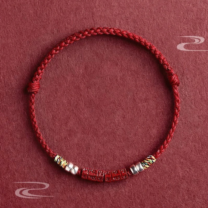 Om Mani Padme Hum red string blessing bracelet with cinnabar bead and sterling silver accents, flat lay overhead view