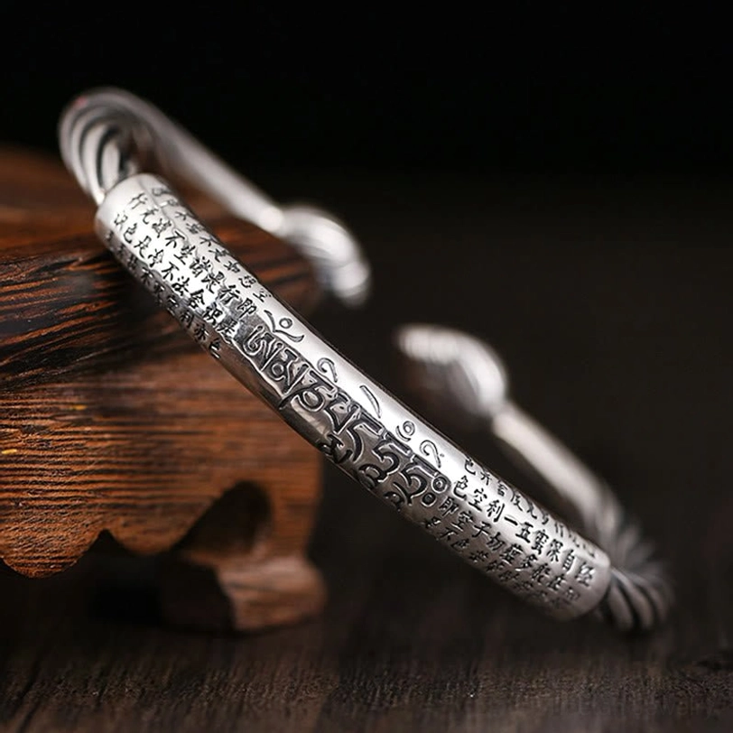 Om Mani Padme Hum copper cuff bracelet with twisted design and Tibetan mantra engraving on wooden display
