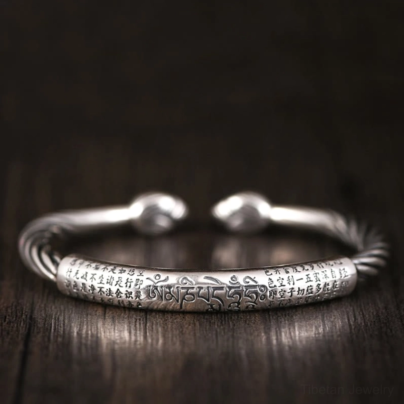 Overhead view of copper cuff with full Tibetan mantra engraving and twisted woven band