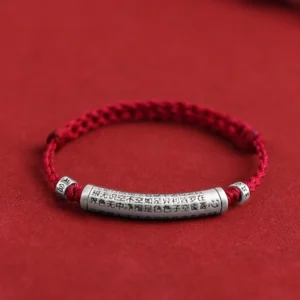 Handmade 999 sterling silver Om Mani Padme Hum bracelet with dark red braided rope and engraved Heart Sutra pendant, flat lay overhead view