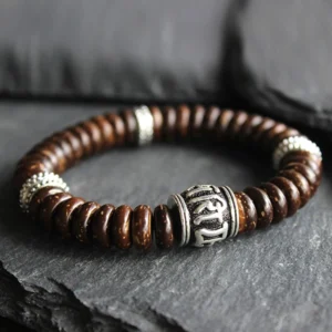 Close-up detail of engraved Sanskrit Om Mani Padme Hum mantra bead with silver spacer rings on brown coconut shell bracelet