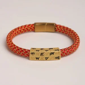 Om Mani Padme Hum braided spiritual bracelet with gold central mantra charm and stainless steel clasp, flat lay top view