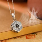990 sterling silver Om Mani Padme Hum projection necklace pendant with octagonal design, front view showing engraved Tibetan script and Buddha image projection on vintage stationery backdrop