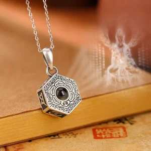 990 sterling silver Om Mani Padme Hum projection necklace pendant with octagonal design, front view showing engraved Tibetan script and Buddha image projection on vintage stationery backdrop