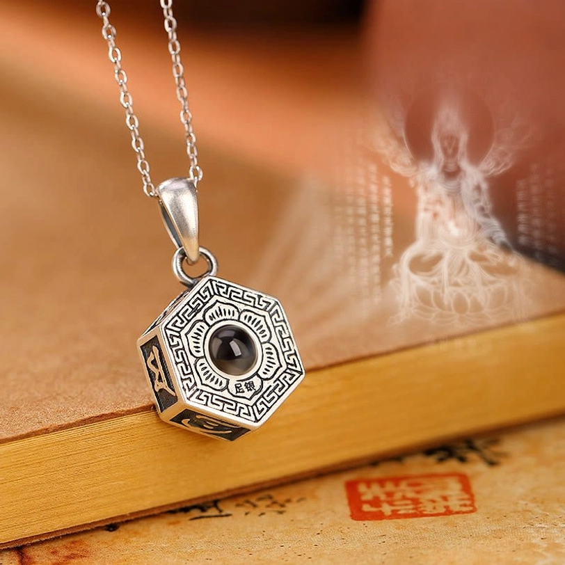 990 sterling silver Om Mani Padme Hum projection necklace pendant with octagonal design, front view showing engraved Tibetan script and Buddha image projection on vintage stationery backdrop