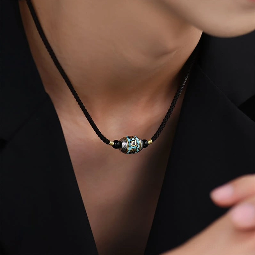 Tibetan Dzi bead necklace worn close to collarbone on black formal clothing, showing minimalist fit and spiritual pendant styling