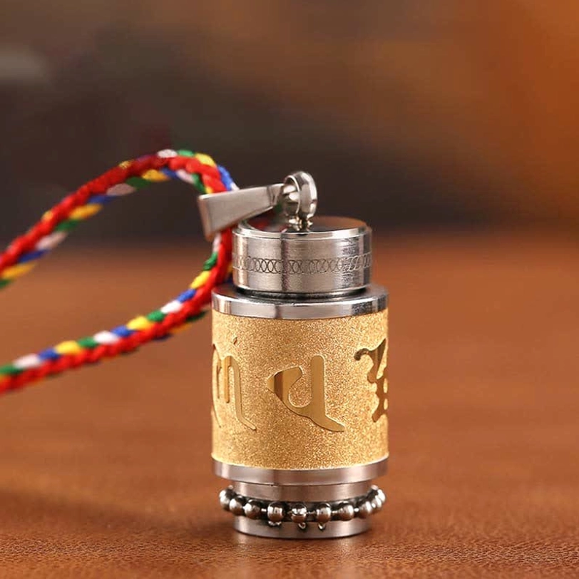 Om Mani Padme Hum titanium steel amulet pendant with frosted gold finish and engraved Buddhist mantra on wooden surface