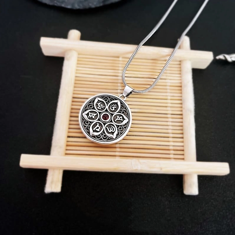 Tibetan pendant necklace on bamboo display stand showing reversed mantra pattern and alternate side detail